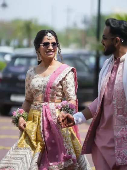 A sweet walking shot of the couple. The bride's makeup is designed to be long-lasting and beautiful, perfect for an outdoor Haldi event.