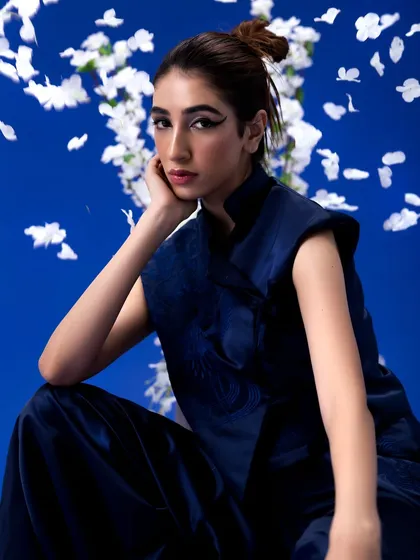A Japanese-inspired "Yume" editorial featuring a bold, graphic winged eyeliner and a clean, knotted top-bun. The makeup is sharp and precise to complement the minimalist styling.