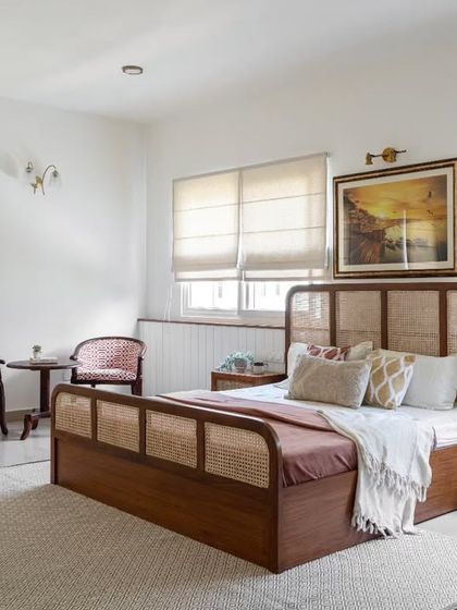 The guest room, designed for the client's parents, exudes an elegant simplicity. A magnificent teakwood and cane bed is paired with antique lounge chairs and a painting of Varanasi that evokes nostalgic memories.