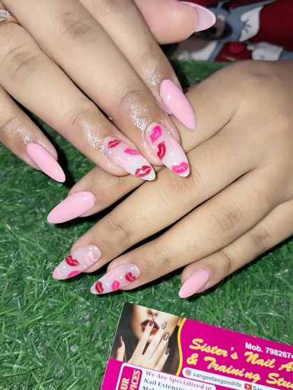 A close-up of the playful lipstick kiss pattern on these pink stiletto nails.