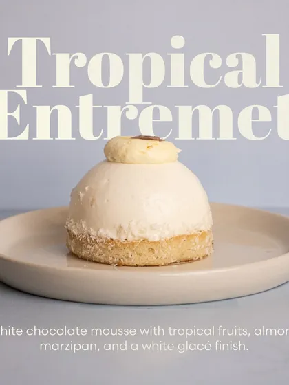 A still shot of the elegant Tropical Entremet, highlighting its smooth white glacé finish and delicate fruit filling.