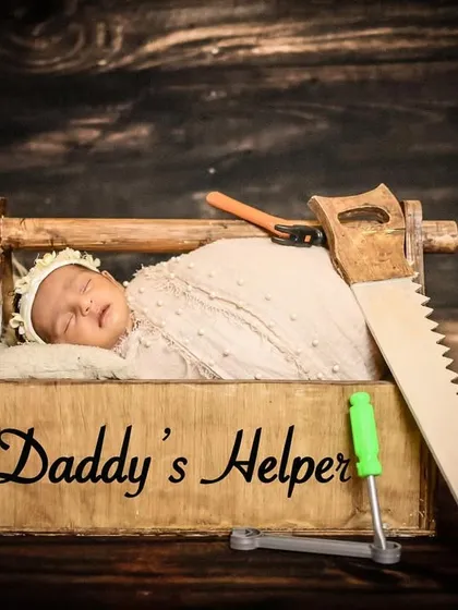 A fun and creative "Daddy's Helper" theme for a newborn shoot, featuring the baby in a toolbox. It's a great way to incorporate a parent's hobby or profession.