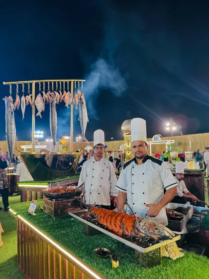 Two of my chefs at the live seafood station, presenting a beautifully prepared whole grilled fish.