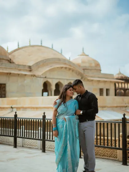 A tender moment with the fort's domes in the background. The cloudy sky adds a soft, diffused light, perfect for capturing the emotion in this candid couple photo session.