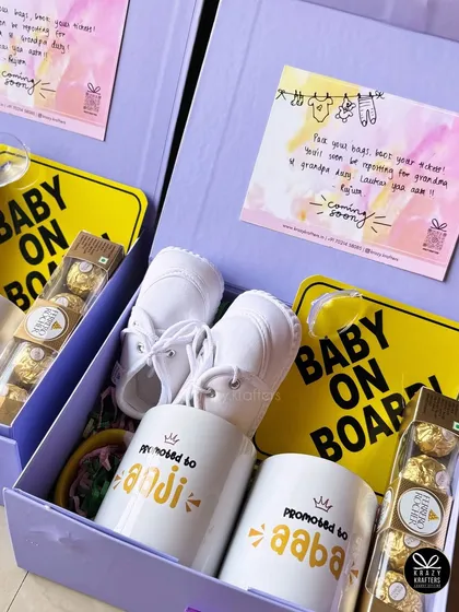 Two beautiful lavender-boxed hampers ready to go out for a pregnancy announcement. Each contains 'Promoted to Aaji & Aaba' mugs, baby shoes, and a 'Baby on Board' sign.