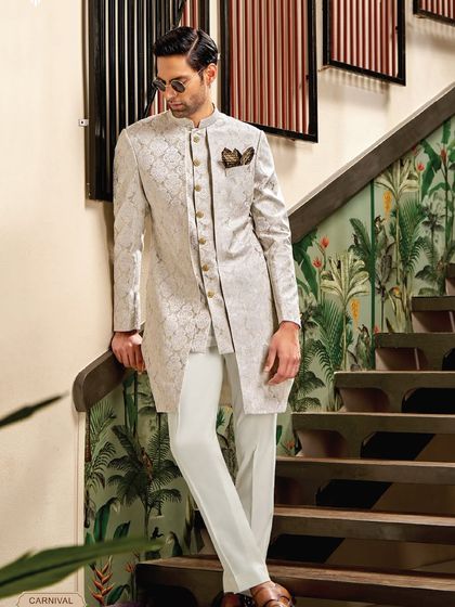 A study in refined elegance. This three-piece sherwani in a textured off-white fabric is designed with a unique layered structure, offering a look of depth and sophistication.