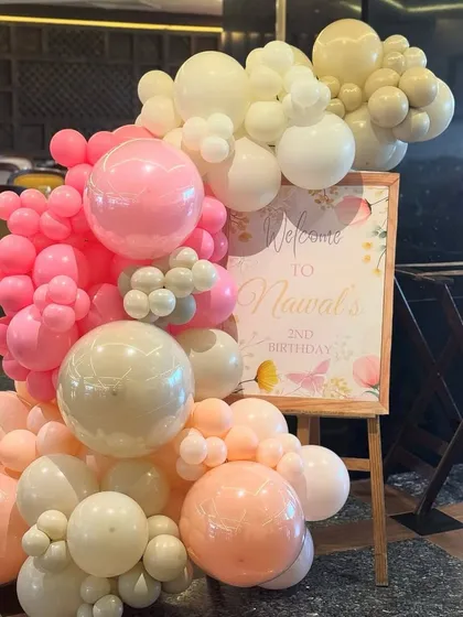 A beautiful welcome sign for a second birthday, nestled in a stunning organic balloon garland of pink, peach, and white. Butterfly details add a touch of whimsy.
