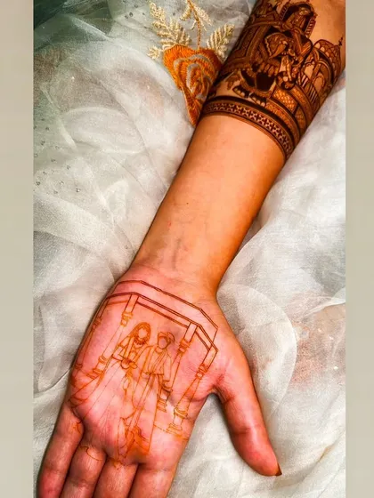 The initial sketch of a couple's portrait on the palm, showing the first step in creating a personalized mehandi.