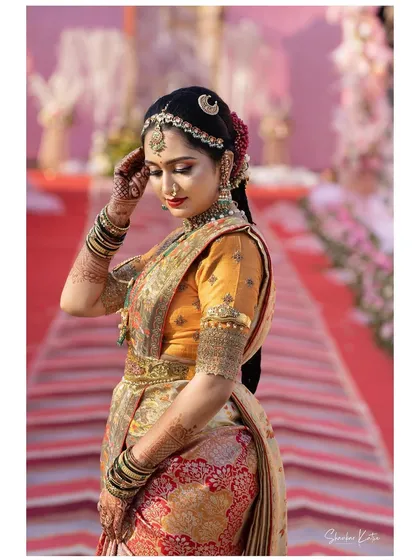 A bride in a stunning Paithani saree. Her custom orange blouse features a scalloped back cutout and heavy embroidery, perfectly matching the grandeur of the saree.