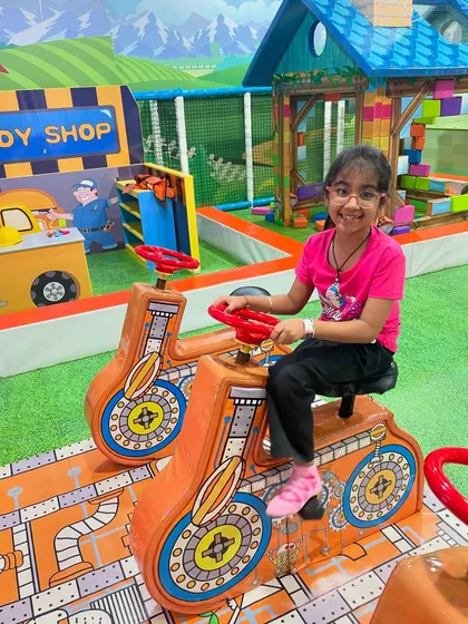 A toddler enjoys a ride on one of our pedal-powered toys, a fun way to move around the play area.