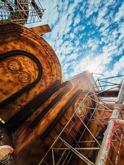 A work in progress shot of a large, steampunk-inspired structure. Even during construction, the scale and artistry of the design are evident against the blue sky.