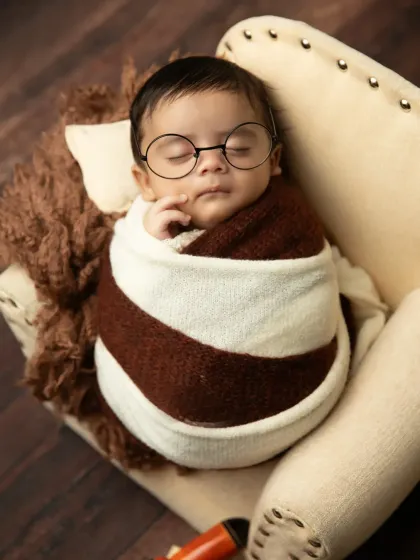 A close-up of our little traveler, looking very scholarly with tiny round glasses. The striped wrap and furry pillow add to the cozy, adventurous feel.
