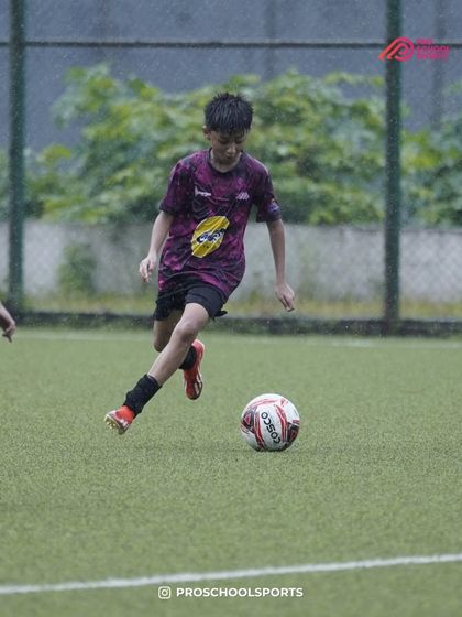 A player dribbles with determination on a rainy day, showing passion for the game.