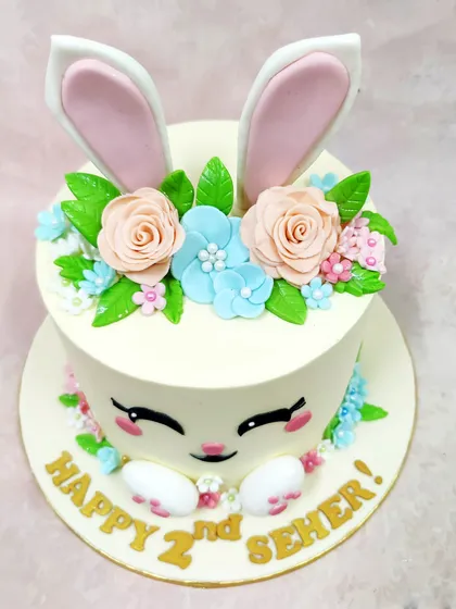 An overhead shot of the bunny cake, highlighting the beautiful arrangement of peach and blue flowers on top.