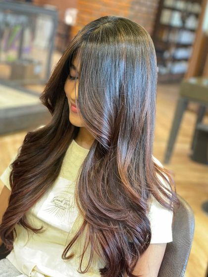 A side view of a gorgeous, glossy layered cut. You can see how the layers are seamlessly blended to create a smooth, flowing shape with curled ends for extra bounce.