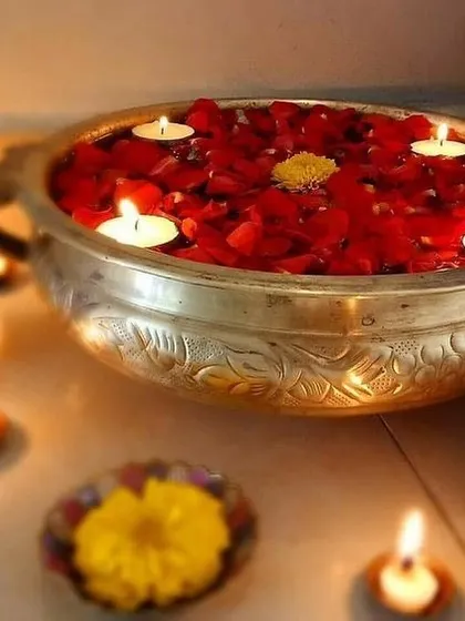 A traditional and beautiful way to welcome guests. This ornate silver urli is filled with water, red rose petals, and floating tea light candles, creating a classic and serene decoration for an entryway.