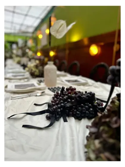 A long view of the table, showing the dramatic effect of the dark grapes and black ribbons against the white tablecloth.
