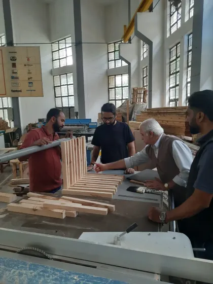 Our approach is built on mentorship. Here, an expert trainer provides one-on-one guidance to students as they assemble a complex slatted furniture piece, ensuring every joint is perfect and every technique is understood.