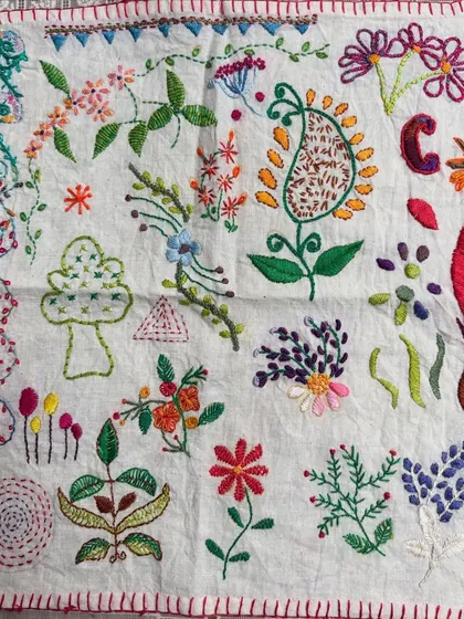 A beautiful freestyle sampler created by one of my students. After learning various stitches, she planned and executed this project, filling the fabric with colorful flowers, leaves, and a central paisley motif.