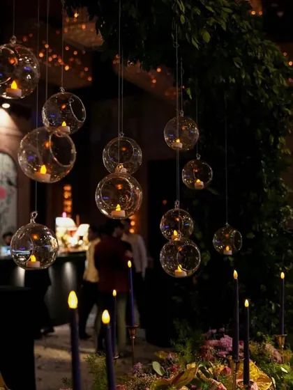 Hanging glass orbs with candles create a magical and romantic lighting effect, perfect for an evening reception or Sangeet.