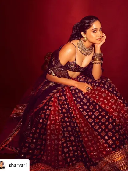 A seated portrait of Sharvari Wagh. The warm lighting highlights the bronzed, glowing makeup look I created for her.