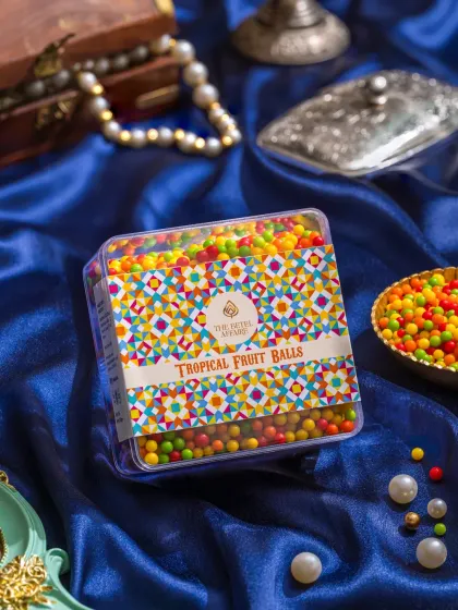 A box of colorful Tropical Fruit Balls, with a vibrant, festive background that matches the product's playful nature.