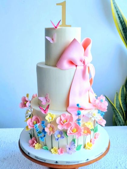 A full view of the floral first birthday cake with a large pink bow.
