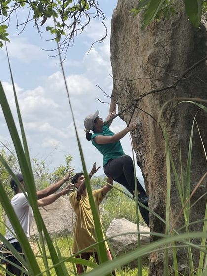 Sudha bouldering with friends spotting her. It's all about teamwork and having a good time together.