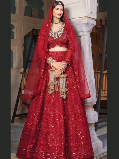The quintessential bridal pose in a stunning, fully embroidered red lehenga. This outfit is perfect for the main wedding ceremony, offering a traditional and regal appearance.