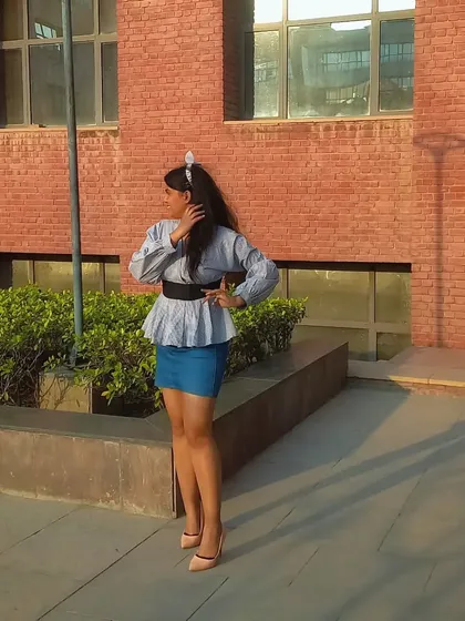 This pose shows off the full silhouette of the peplum top and mini skirt combination. The headband adds a preppy, playful touch to the outfit.