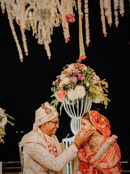 A tender moment between the groom and bride under a beautiful floral mandap at night.