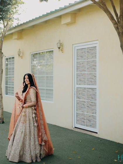 A classic bridal portrait, showcasing the bride's full attire against a simple, elegant architectural background.