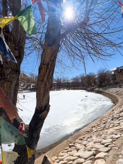 A frozen lake in Spiti, with Tibetan prayer flags adding a splash of color to the winter scene.