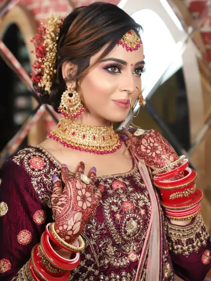 A beautiful profile of a bride in a deep wine-colored lehenga. The makeup features purple and pink tones on the eyes to match her outfit.