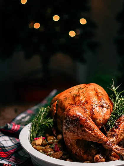 The centerpiece of a holiday feast: our whole roasted turkey, beautifully browned and garnished with fresh rosemary. This is available for home delivery during the festive season.