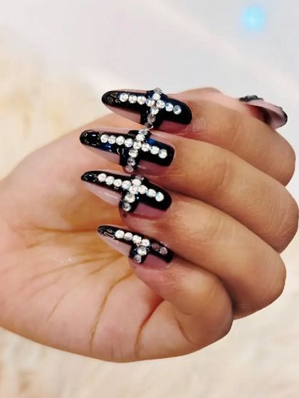 For those who love a bold statement, these long, black stiletto nails feature dramatic cross shapes made entirely of sparkling rhinestones.