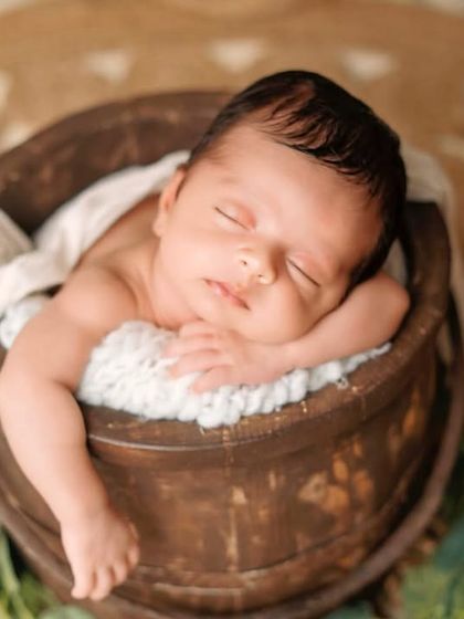 A rustic wooden bucket is a classic prop for newborn photography. It provides a cozy and secure space for the baby to rest in a natural, curled-up pose.