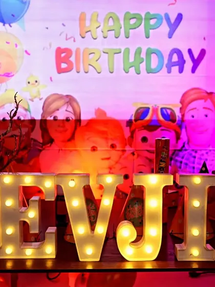 A close-up of the marquee letters spelling out 'DEVJIT' at his Cocomelon-themed party, adding a bright and personal touch to the decor.