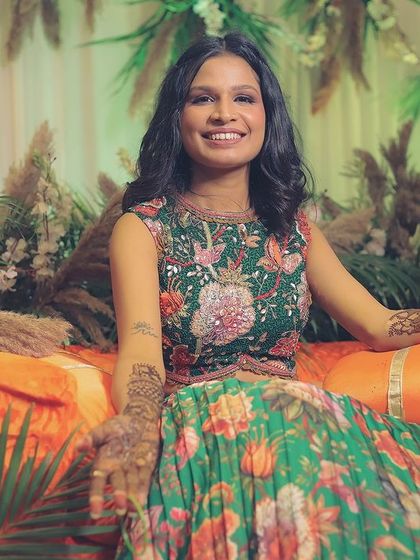The bride smiles as she gets her mehendi done, sitting amidst a beautiful bohemian-themed decor with pampas grass and floral arrangements.