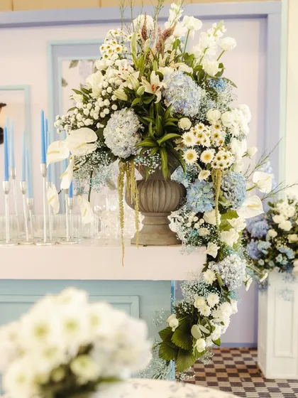 A cascading floral arrangement on a bar counter, artfully combining white lilies, blue hydrangeas, and baby's breath for a dramatic and elegant effect.