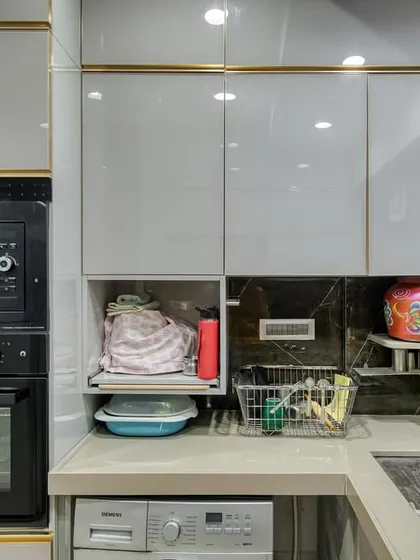 The sink and appliance area of the C-shaped kitchen, showing the integrated oven and washing machine.