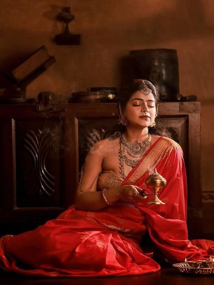 A regal portrait series inspired by the queens of Tulunadu. The model is adorned in a stunning red saree and antique-style jewelry, captured in a heritage location to enhance the royal theme.