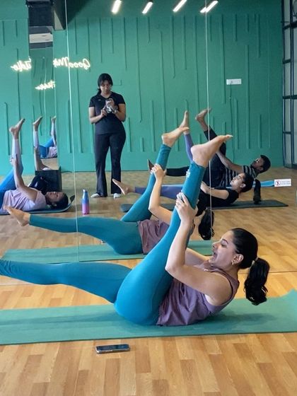 A class working on single leg stretches, a classic Pilates exercise for abdominal strength and hamstring flexibility. You can see me in the background, keeping an eye on everyone's form.