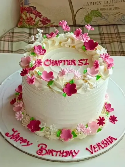 A chic and simple birthday cake for "Chapter 51," featuring a wreath of delicate pink and white buttercream flowers.