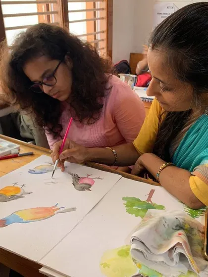 I guide a student as she practices painting birds in watercolor. These sessions are interactive, allowing for immediate questions and corrections, which accelerates the learning process.
