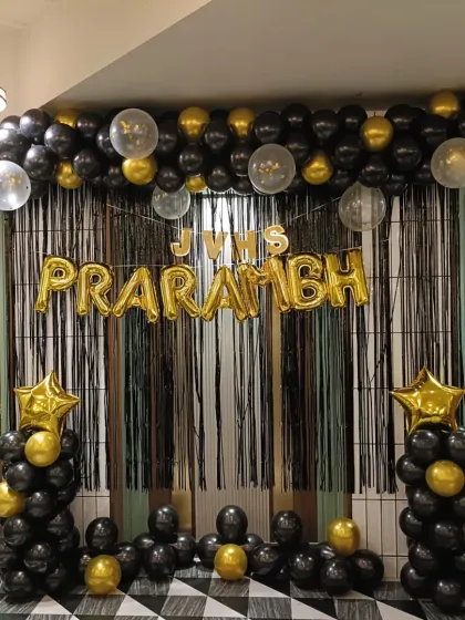 For the "PRARAMBH" launch event, I created this bold black and gold theme. The setup includes a black fringe curtain, foil letter balloons for the event name, and matching balloon pillars for a grand statement.