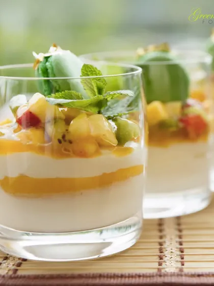 A light and refreshing dessert option. This layered fruit and cream parfait in a glass is topped with a delicate macaron, combining different textures and flavors for a sophisticated sweet course.