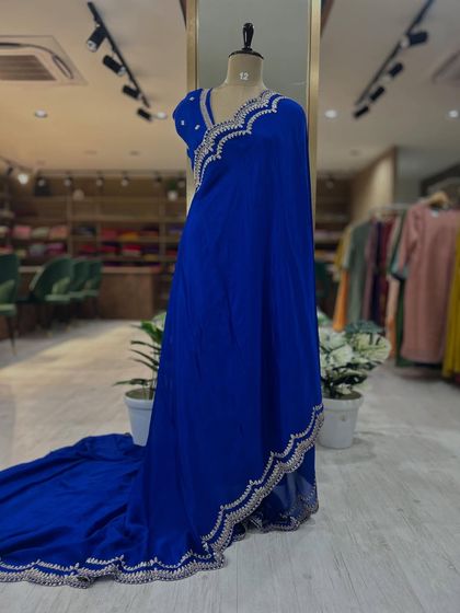 Full-length views of our Chinon party wear sarees, displayed on a mannequin. Available in stunning red and royal blue, these sarees feature intricate scalloped borders and come with a matching pre-stitched embroidered blouse.