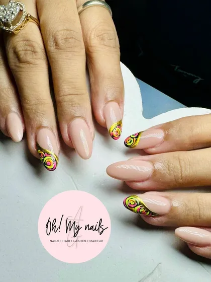 Art on point. This design features a neutral base with a unique, hand-painted spiral pattern in yellow, pink, and black on the tips of the nails.
