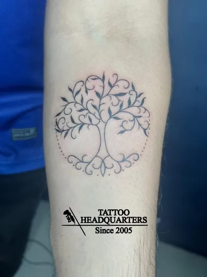 A beautiful "tree of life" tattoo with swirling branches and roots contained within a dotted circle.